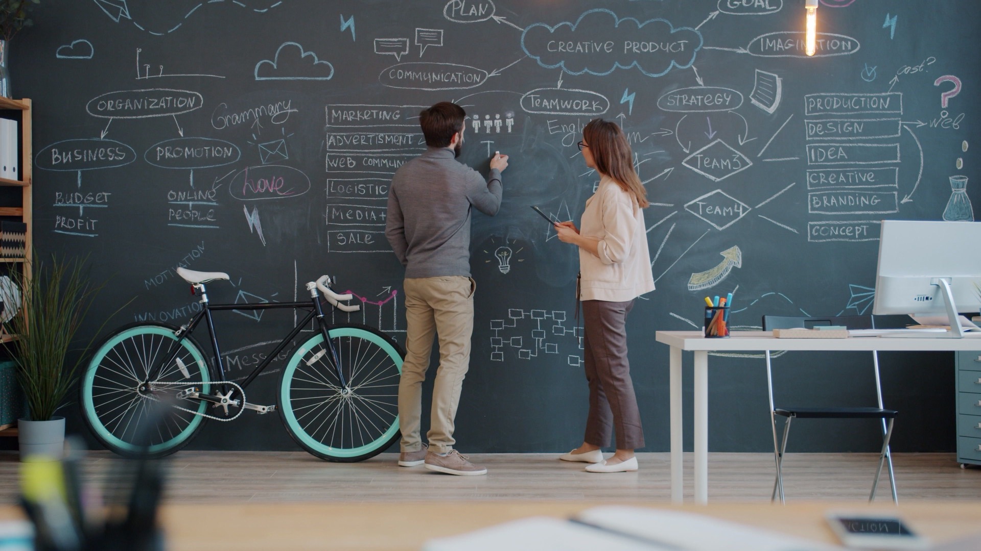 Two founders mapping out a product plan on a chalkboard wall